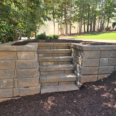 Stone retaining wall with built-in steps in a garden.