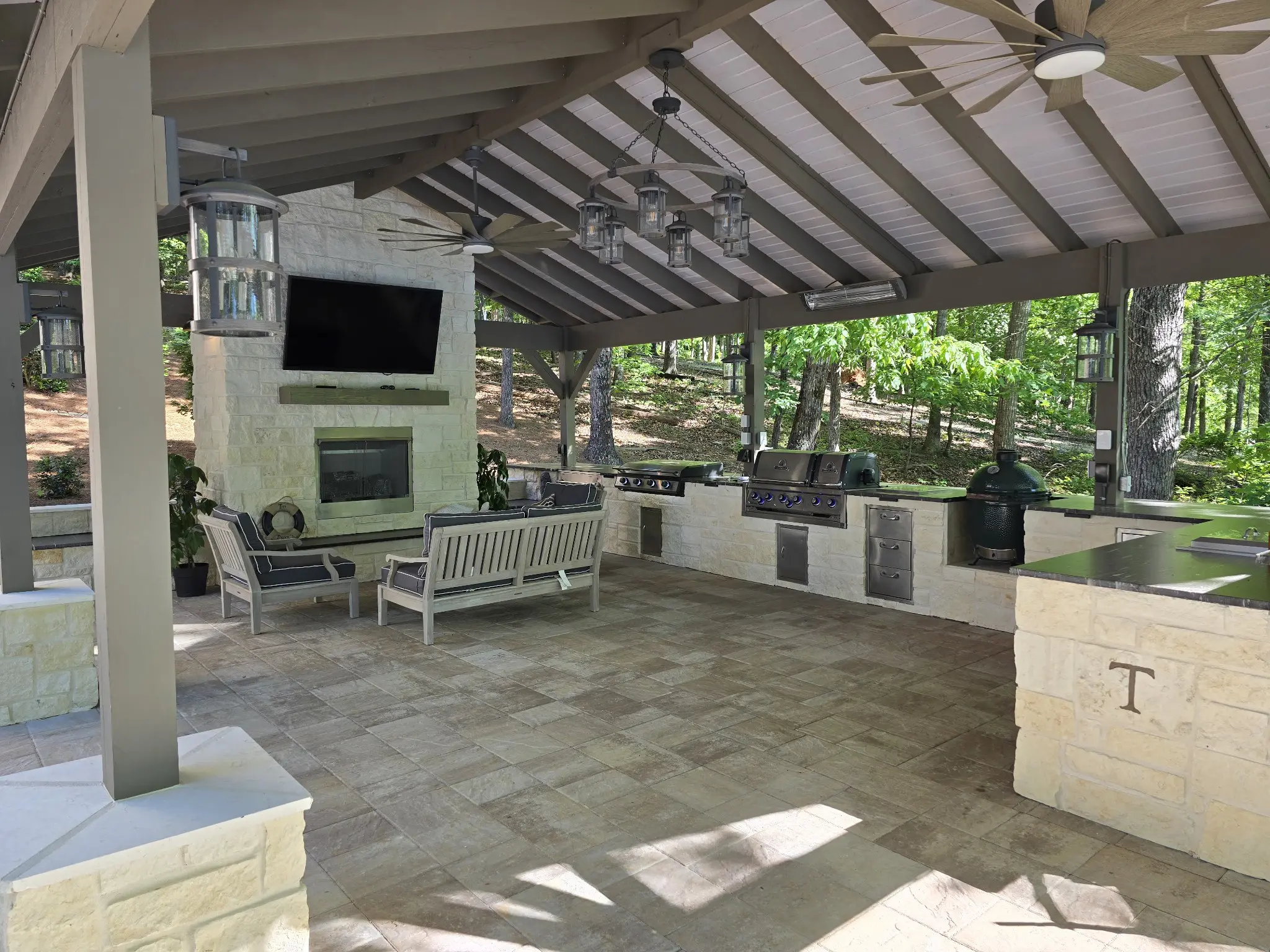 Spacious outdoor patio with fireplace and seating under a covered roof.