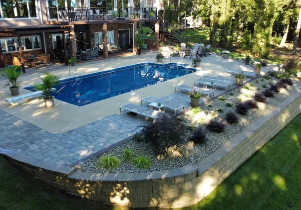 Elegant backyard pool area with lounge chairs and greenery.